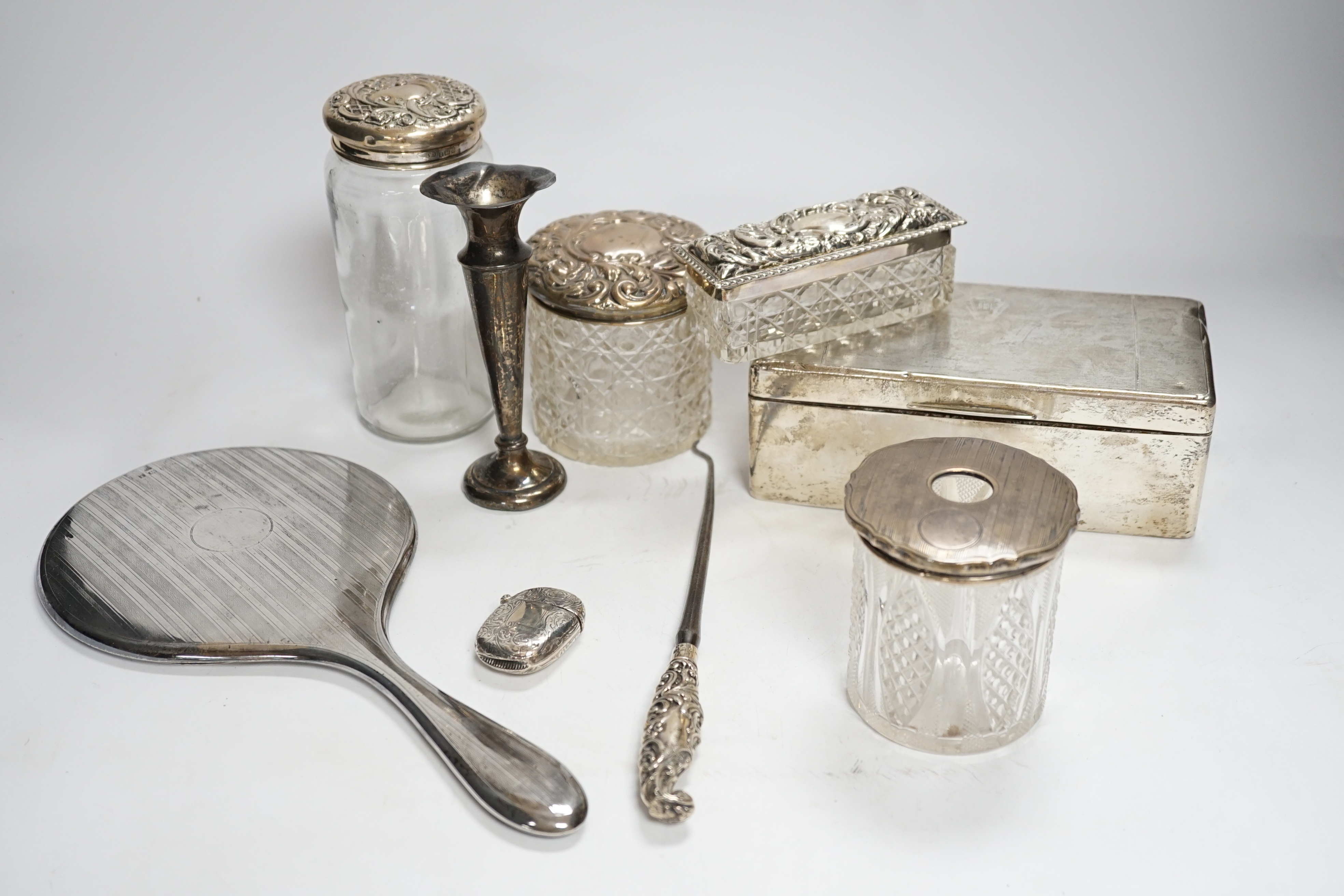 Sundry small silver including a silver mounted cigarette box, four assorted mounted glass toilet jars, a vesta case, button hook, hand mirror and trumpet vase.